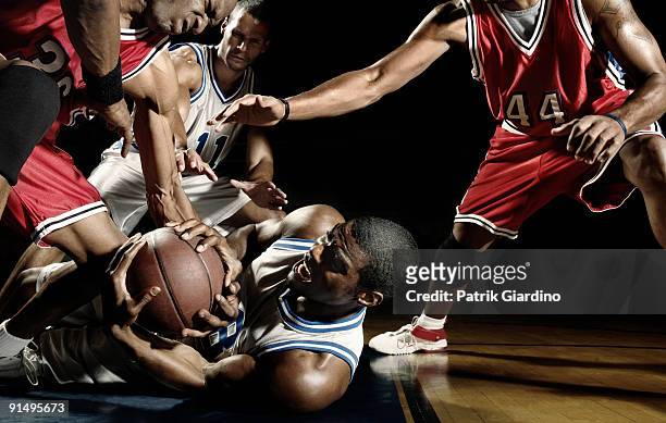 multi-ethnic basketball players struggling for basketball - basketballmannschaft stock-fotos und bilder