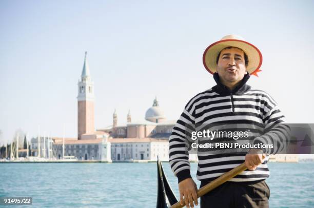 italian gondolier with church in background - gondola traditional boat stockfoto's en -beelden