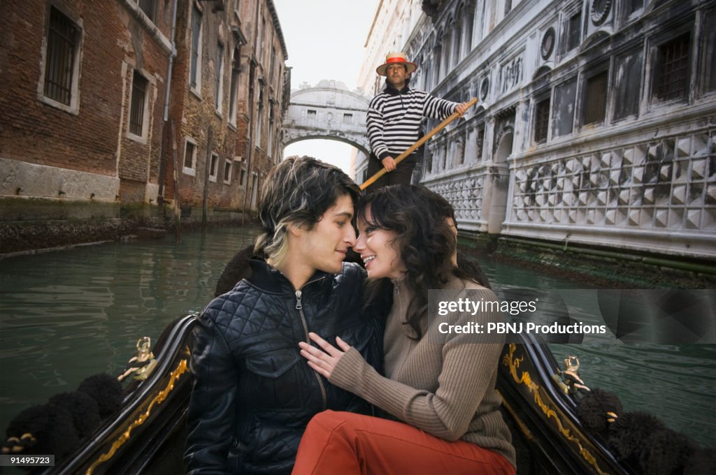 Romantic Italian couple riding in gondola through canal