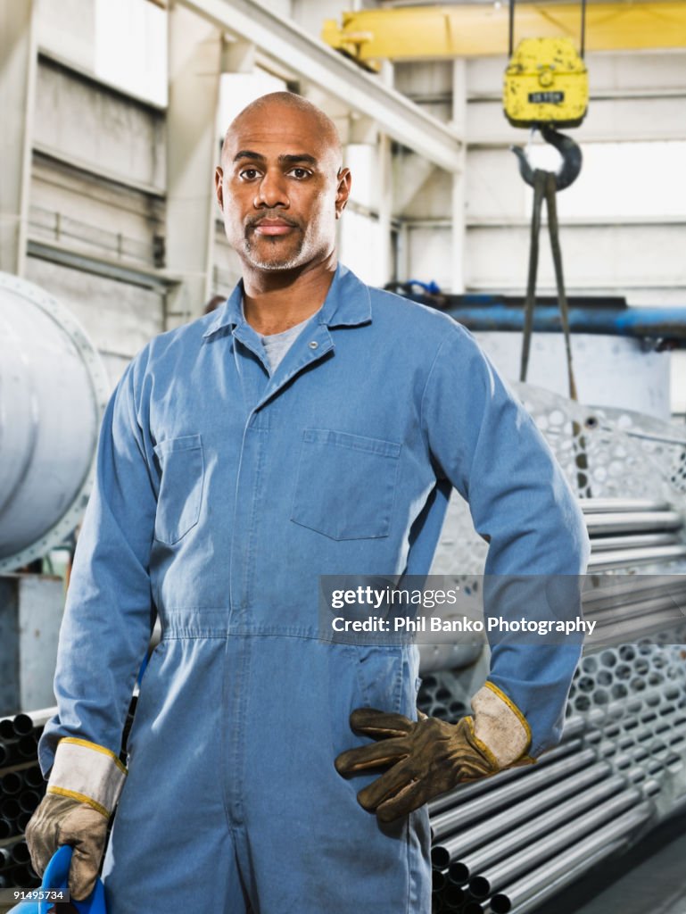 African man in gloves and coveralls in factory