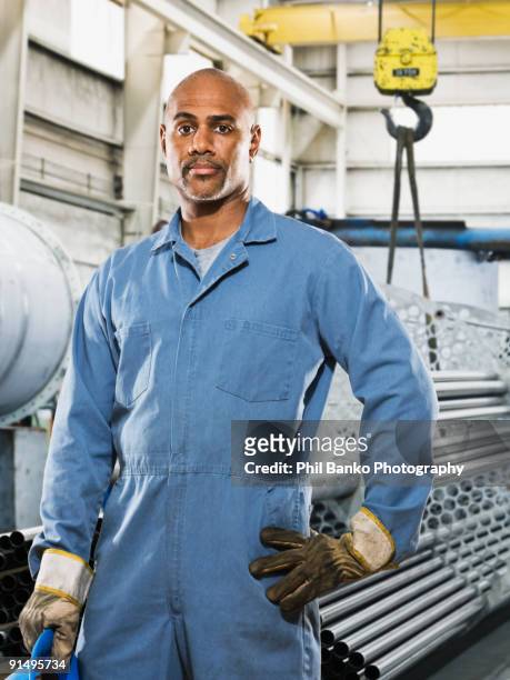 african man in gloves and coveralls in factory - overall stock pictures, royalty-free photos & images