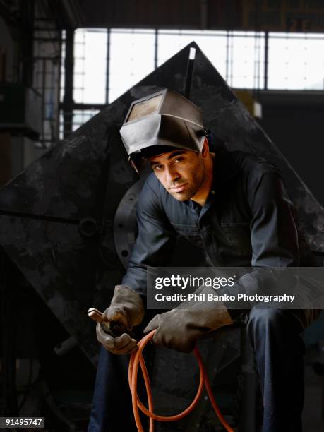 welder in helmet and gloves in warehouse - welding shop stock pictures, royalty-free photos & images