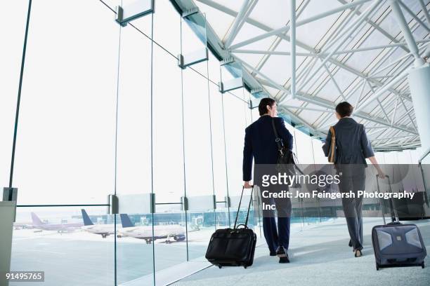 multi-ethnic business people walking in airport - business air travel stock pictures, royalty-free photos & images