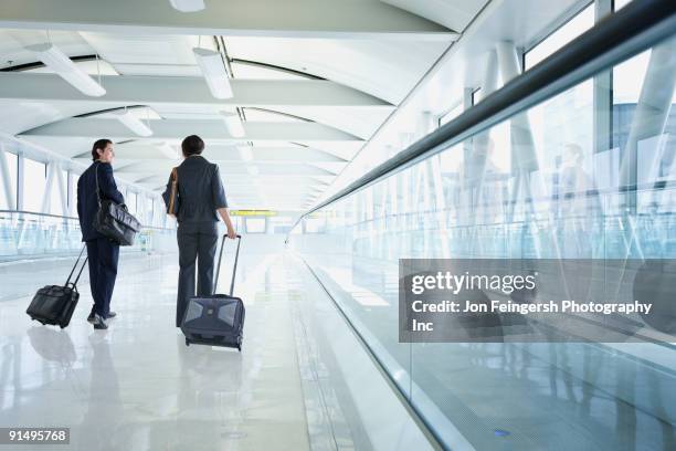 multi-ethnic business people walking in airport - travolator stock pictures, royalty-free photos & images