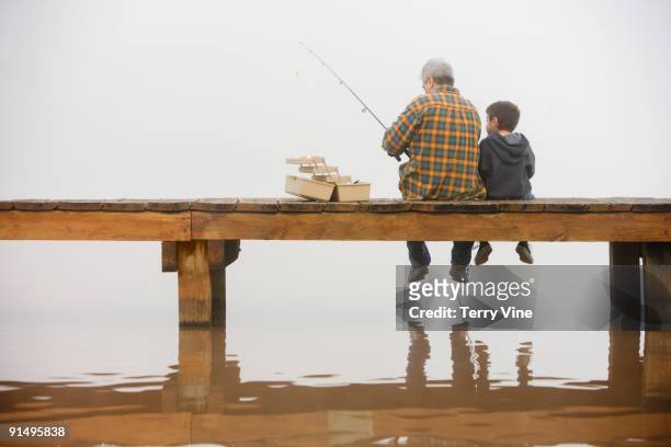 grandfather and grandson fishing off dock - 榜樣 個照片及圖片檔