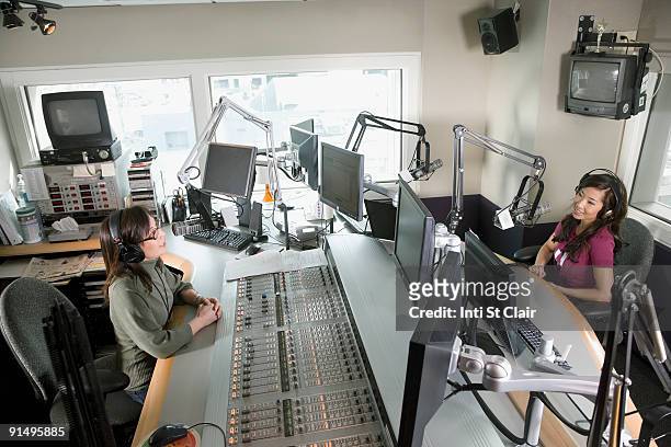 asian dj working at radio station with co-worker - radio dj photos et images de collection