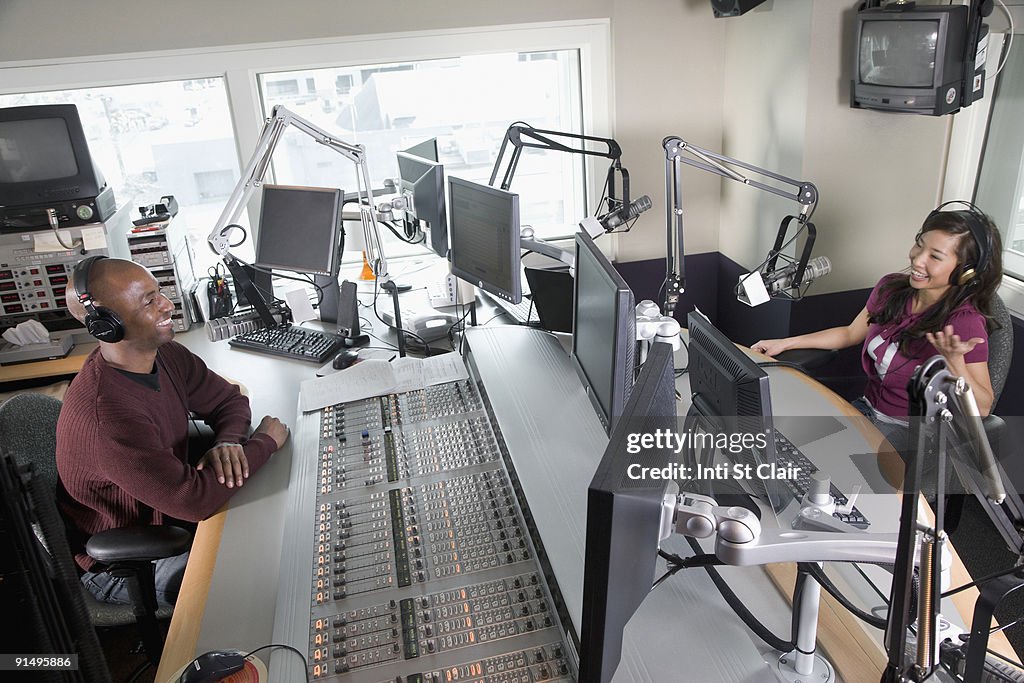 Asian dj working at radio station with co-worker