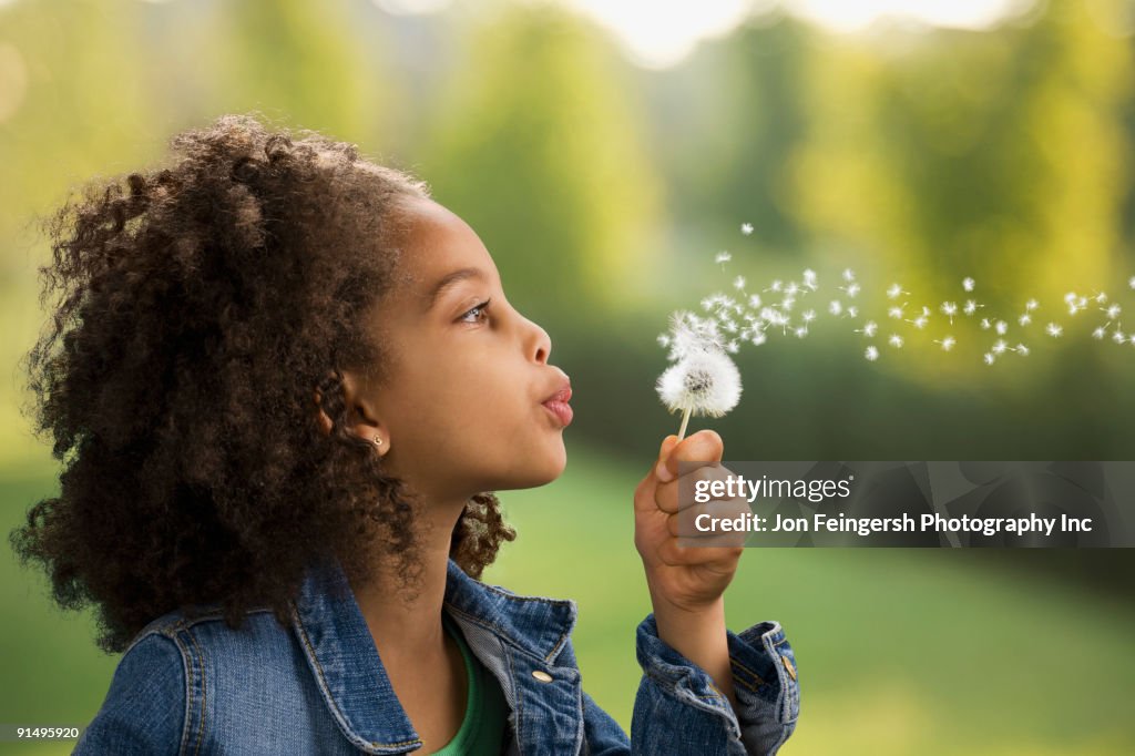 African girl blowing dandelion seeds