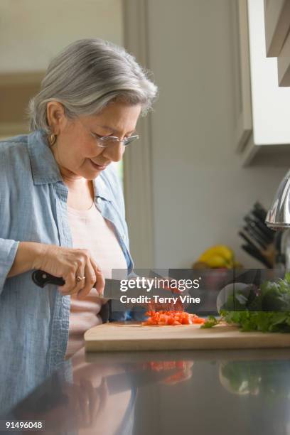 senior hispanic woman chopping fresh vegetables - homemaker - fotografias e filmes do acervo