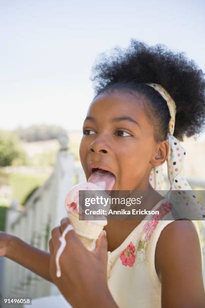 mixed race girl licking melting ice cream cone - girl eating messy ice cream cone stock-fotos und bilder
