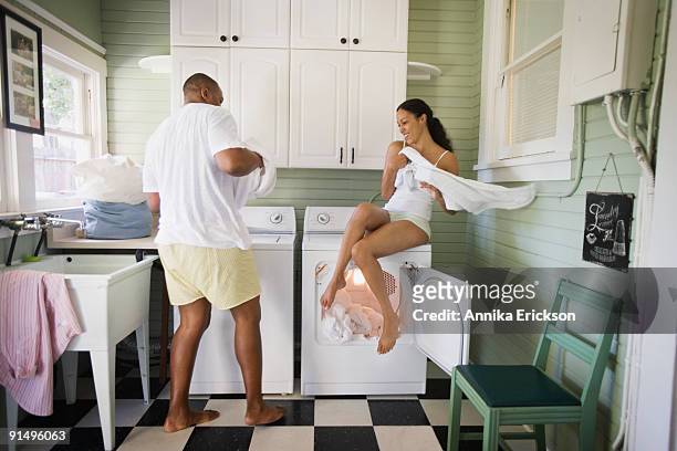 playful couple folding laundry - haciendo burla fotografías e imágenes de stock