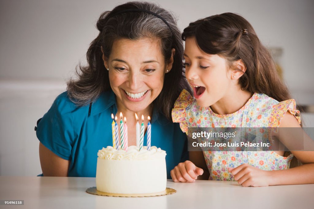 Hispanic grandmother and granddaughter with birthday cake