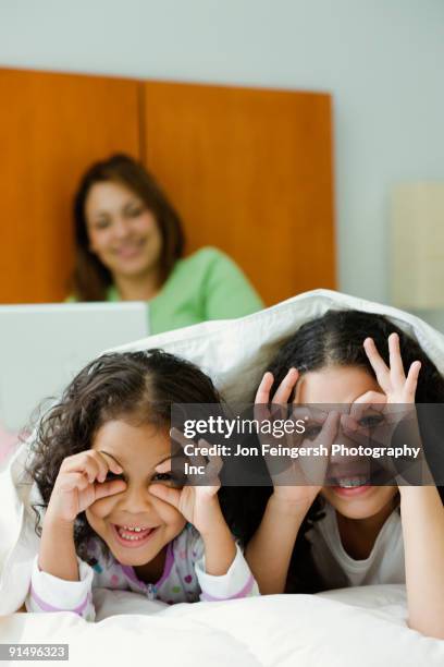 hispanic sisters playing underneath blanket - cover monster face stock pictures, royalty-free photos & images