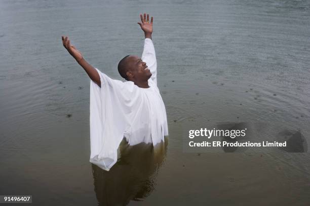 african man getting baptized in lake - túnica fotografías e imágenes de stock