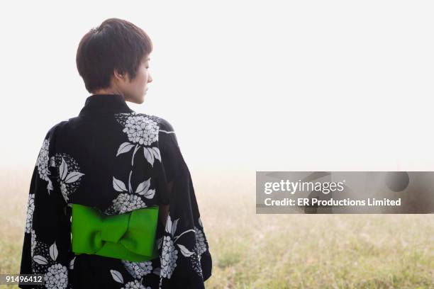 asian woman wearing traditional robe standing in field - obi sash fotografías e imágenes de stock