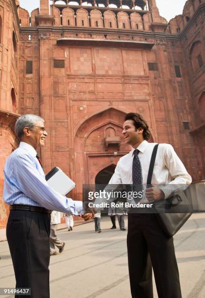 indian businessman shaking hands at the red fort - low angle view of two businessmen standing face to face outdoors stock pictures, royalty-free photos & images