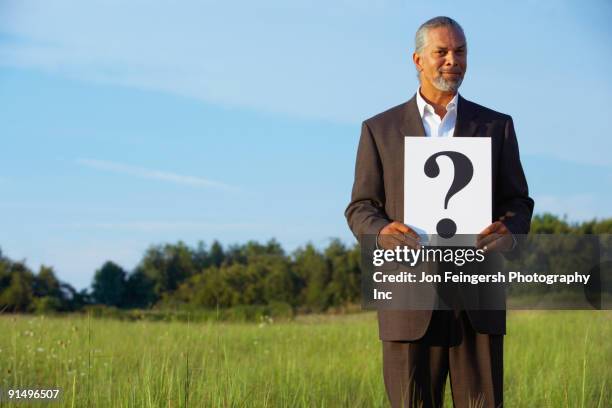 senior african businessman holding question mark in field - manquestionmark stock pictures, royalty-free photos & images