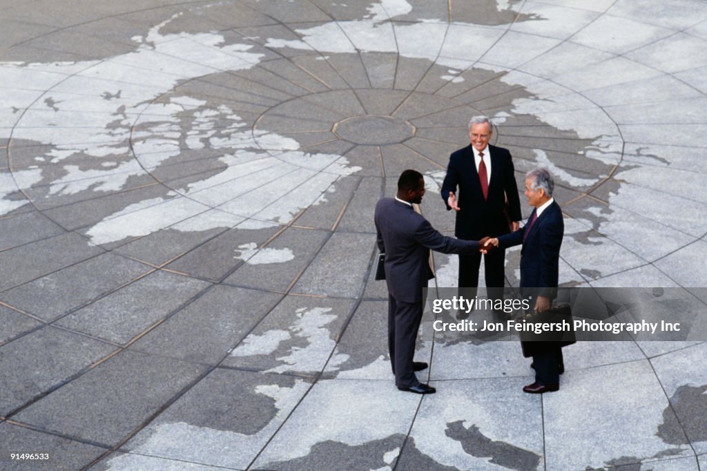 Businessmen shaking hands on map of globe