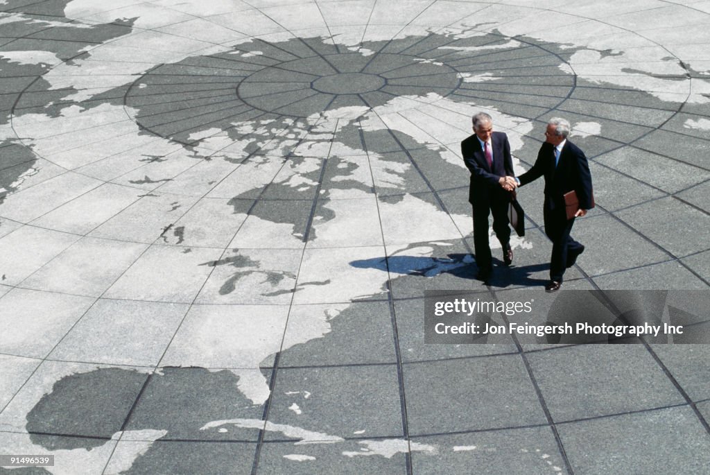 Businessmen shaking hands on map of globe