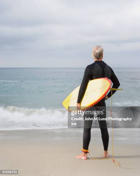 man holding surfboard at beach - surfboard isolated stock pictures, royalty-free photos & images
