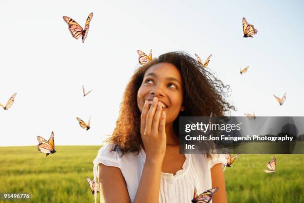 african woman standing among butterflies in meadow - wandelschoenen stock-fotos und bilder