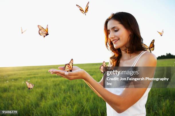 woman standing among butterflies in meadow - butterfly hand imagens e fotografias de stock