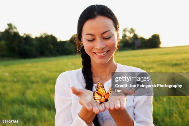 asian woman holding butterfly in hands - butterfly hand stock-fotos und bilder