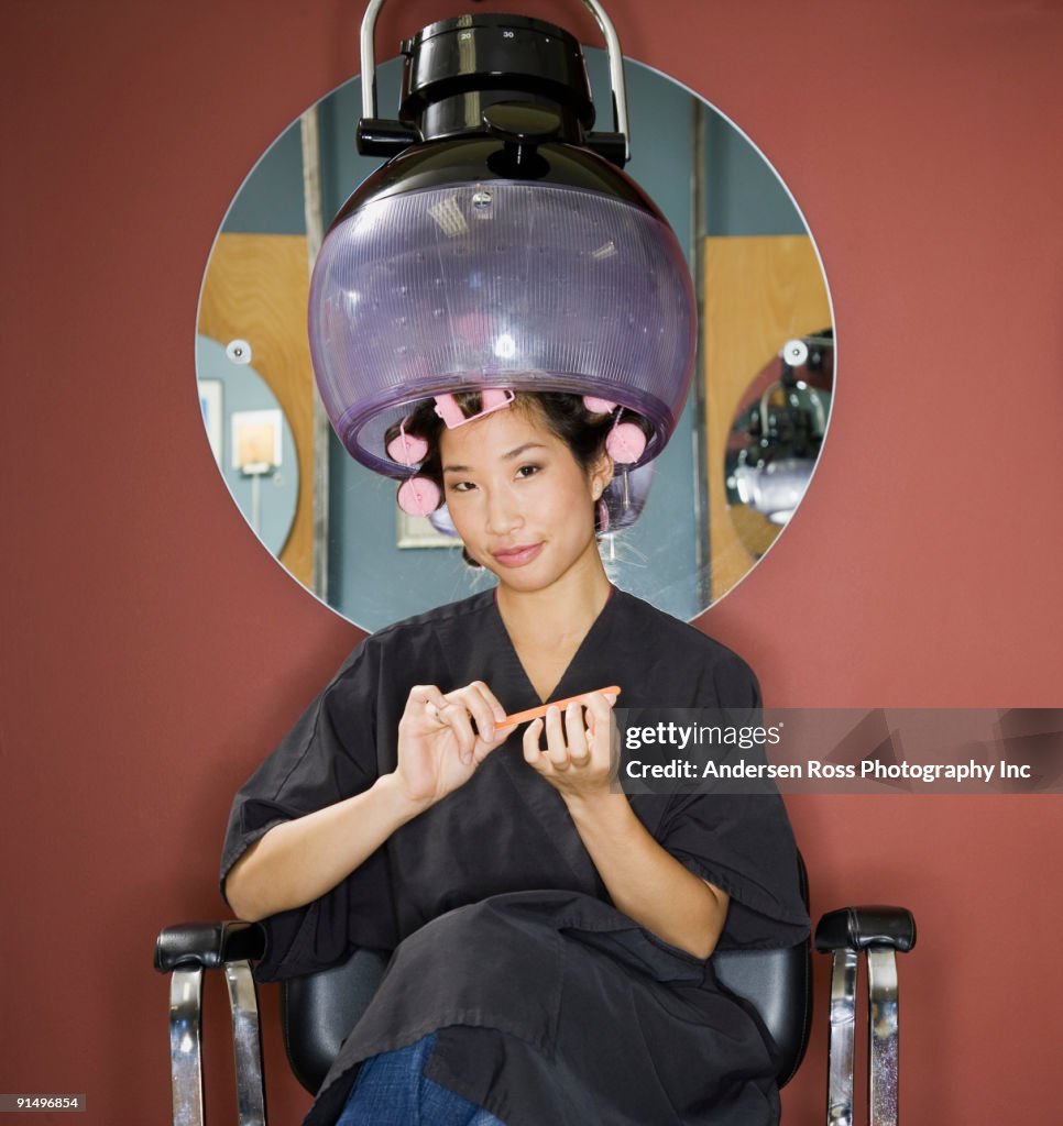 Asian woman under hair dryer in salon