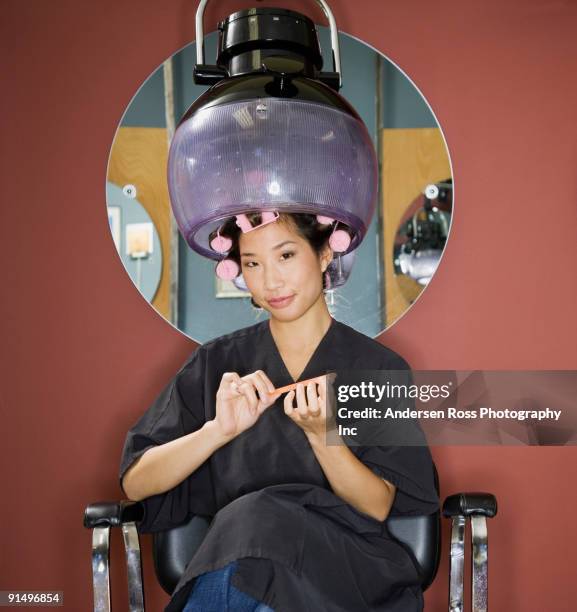 asian woman under hair dryer in salon - coiffeur photos et images de collection