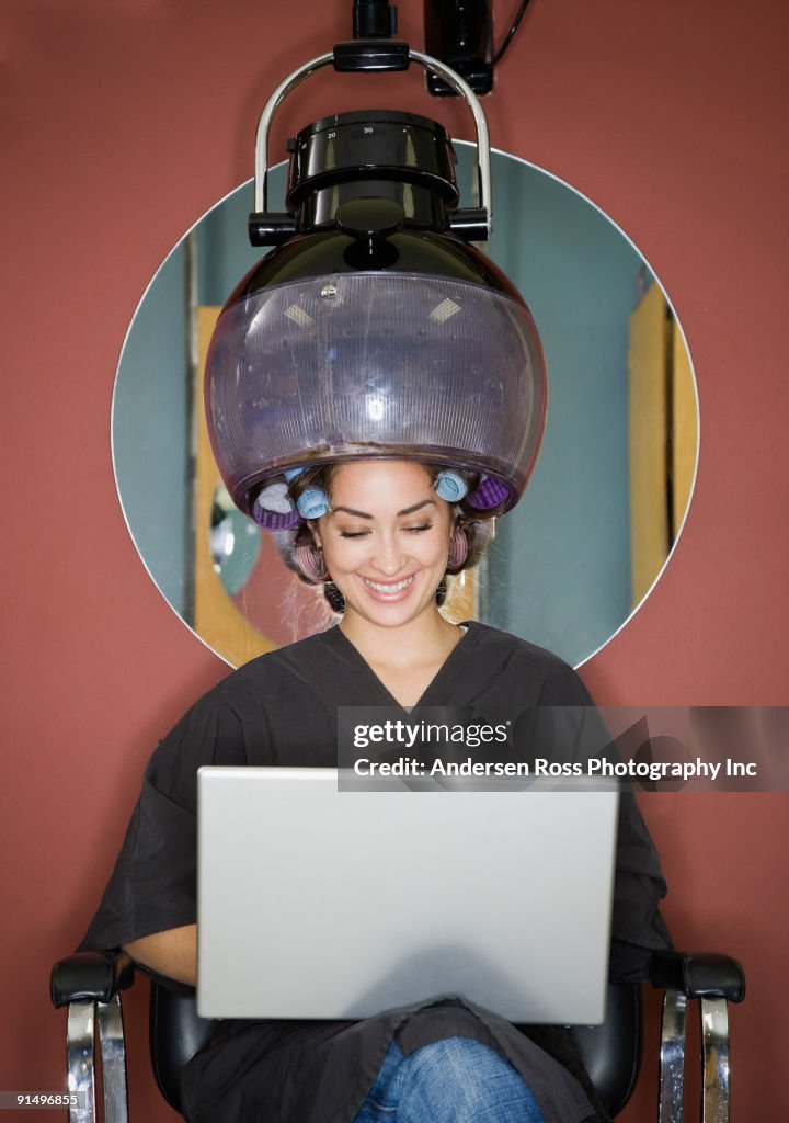 Hispanic woman under hair dryer in salon