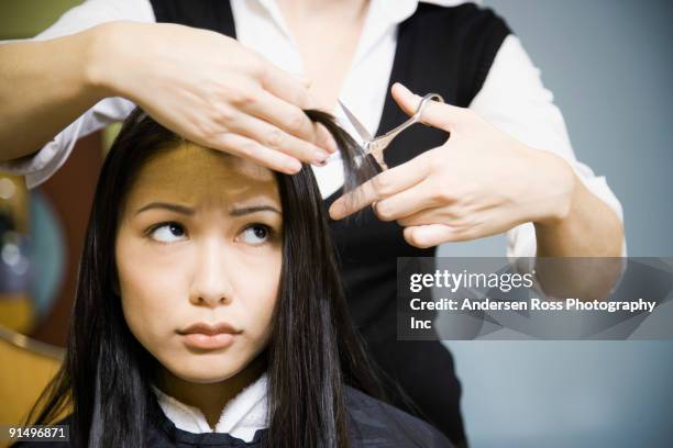 female hair stylist cutting woman's hair in salon - bad haircut photos et images de collection