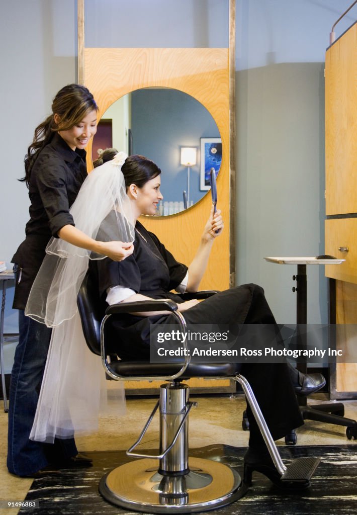 Bride looking at hair and veil at salon