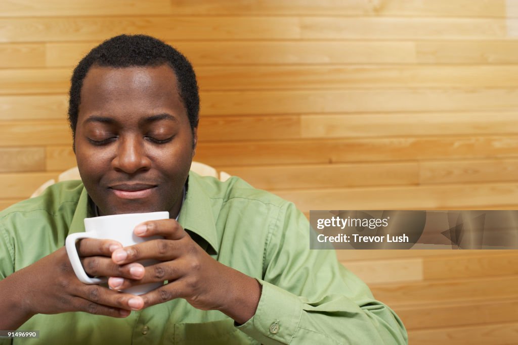 African man smelling cup of coffee