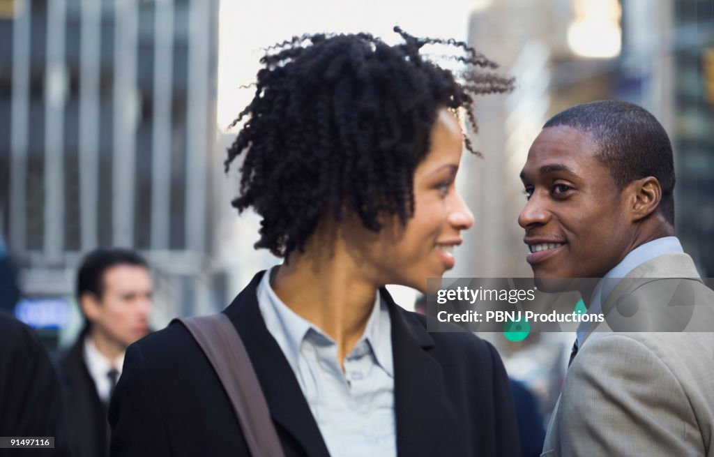 African American businesswoman smiling at businessman on street