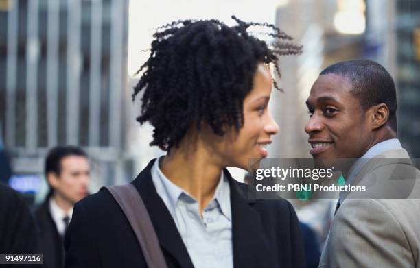 african american businesswoman smiling at businessman on street - man side way looking imagens e fotografias de stock