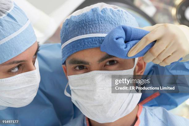 asian nurse wiping doctor's brow - mops brow at stock pictures, royalty-free photos & images