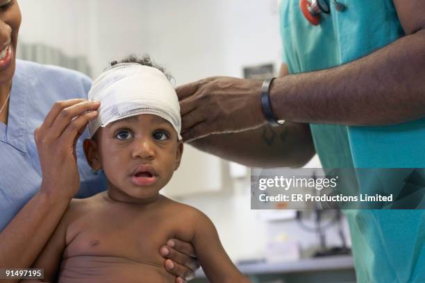 african american baby having head bandaged at hospital - african injured stock pictures, royalty-free photos & images