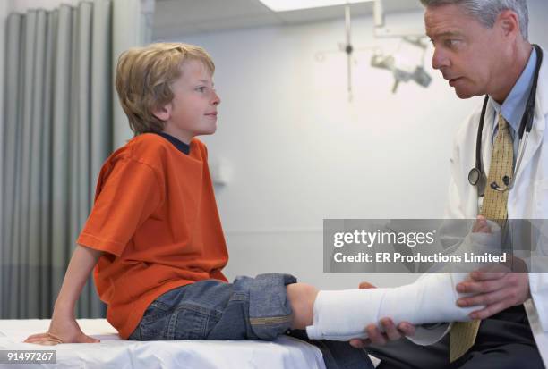 male doctor examining boy with cast - child having medical bones stock pictures, royalty-free photos & images