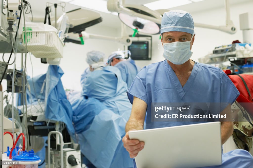 Male doctor with laptop in operating room