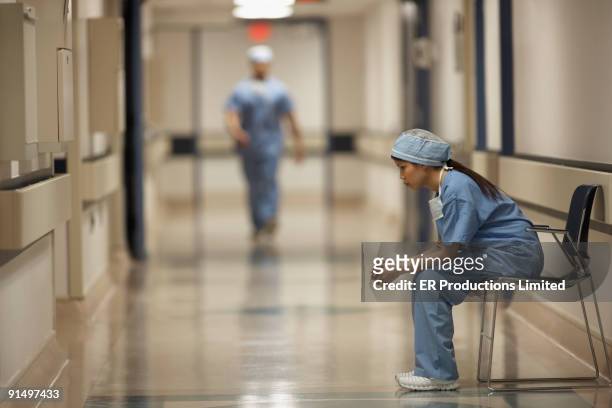 asian female medical professional sitting in chair - sad nurse stock pictures, royalty-free photos & images