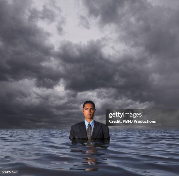 hispanic businessman standing in water - business flood stock pictures, royalty-free photos & images