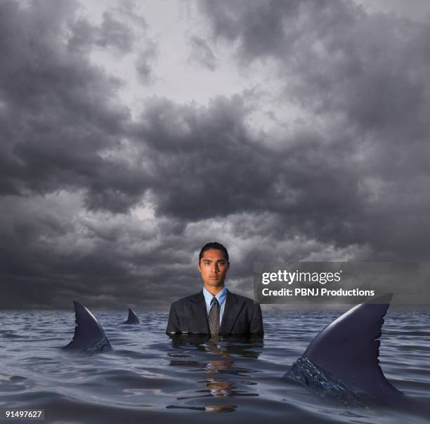 hispanic businessman standing in water with sharks - sink ストックフォトと画像