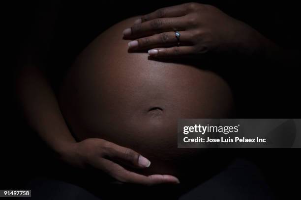 close up of mixed race woman's pregnant stomach - preganant woman stockfoto's en -beelden