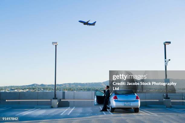 african businessman standing by car at airport - airport parking stock-fotos und bilder