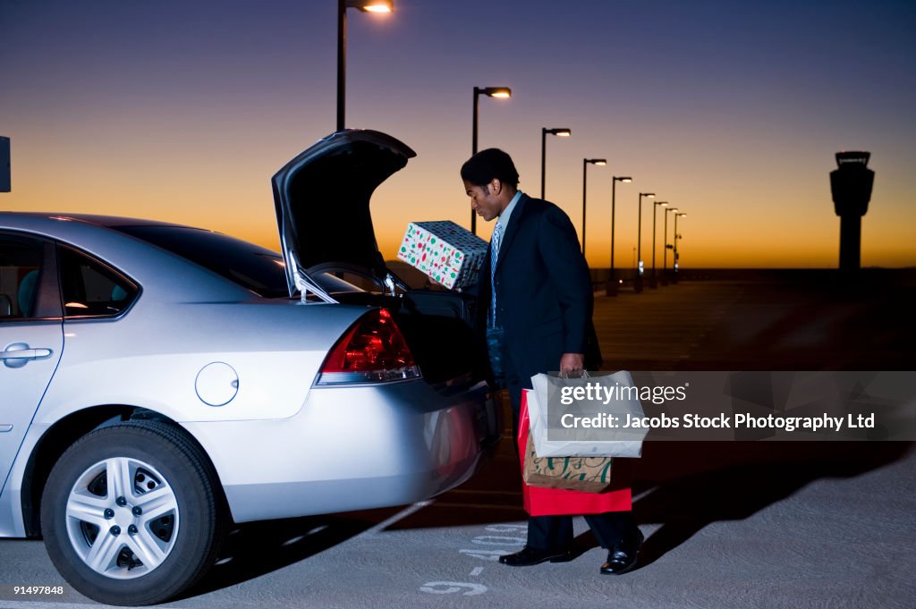 African businessman loading packages into car in parking lot