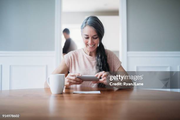 mature woman photographing check for remote deposit - cheque deposit stock pictures, royalty-free photos & images