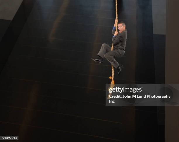 asian businessman dangling from end of rope - homme en contre plongée fait le pitre photos et images de collection