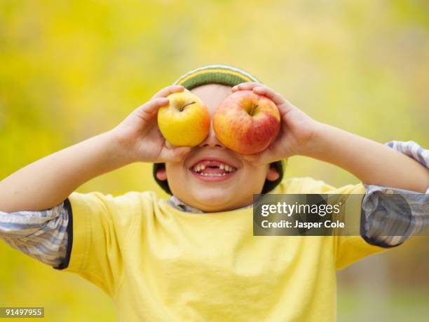toothless hispanic boy covering eyes with apples - no teeth stock pictures, royalty-free photos & images