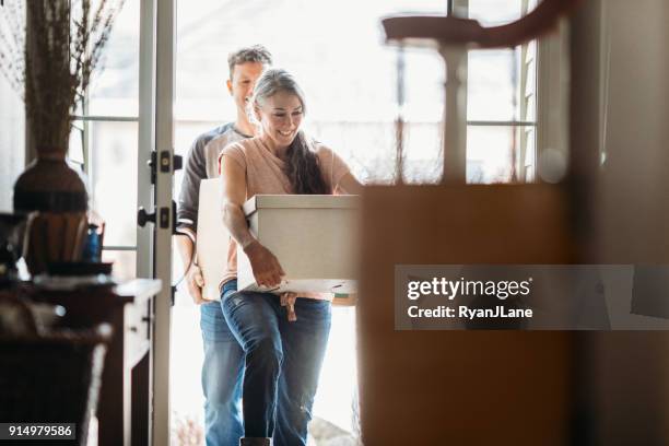 mature couple with moving boxes in new home - working on the move stock pictures, royalty-free photos & images