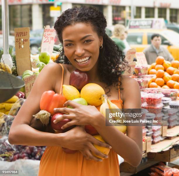 african woman holding armful of fruits and vegetables - carrying fotografías e imágenes de stock